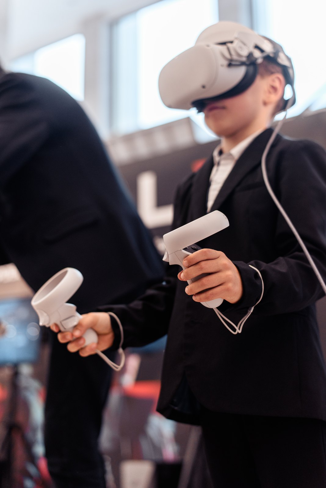 Ребёнок в VR-шлеме держит контроллеры, оператор рядом