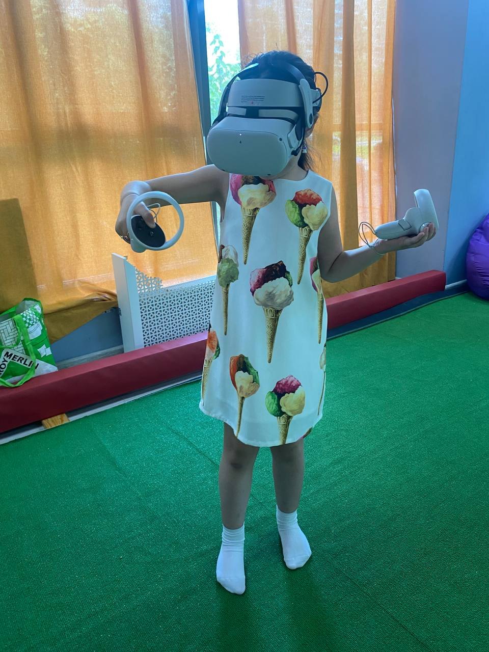 Девочка играет в VR на детском празднике, зона застелена матами