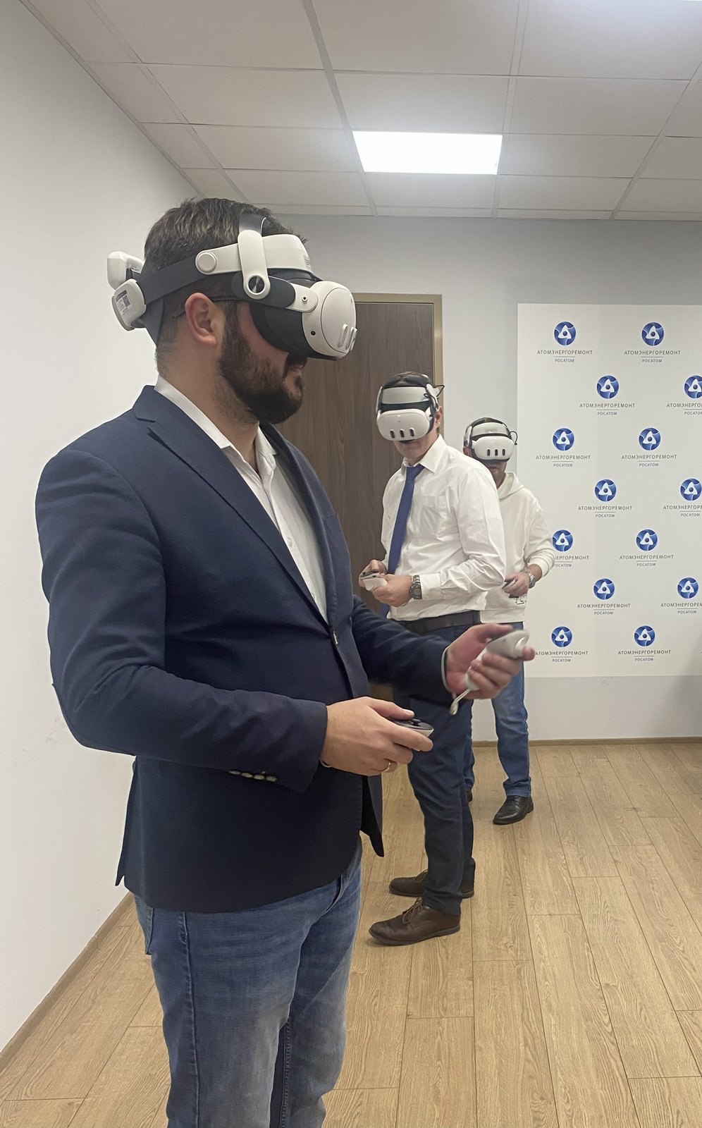 Сотрудники компании в VR-шлемах у брендированной стены на корпоративе