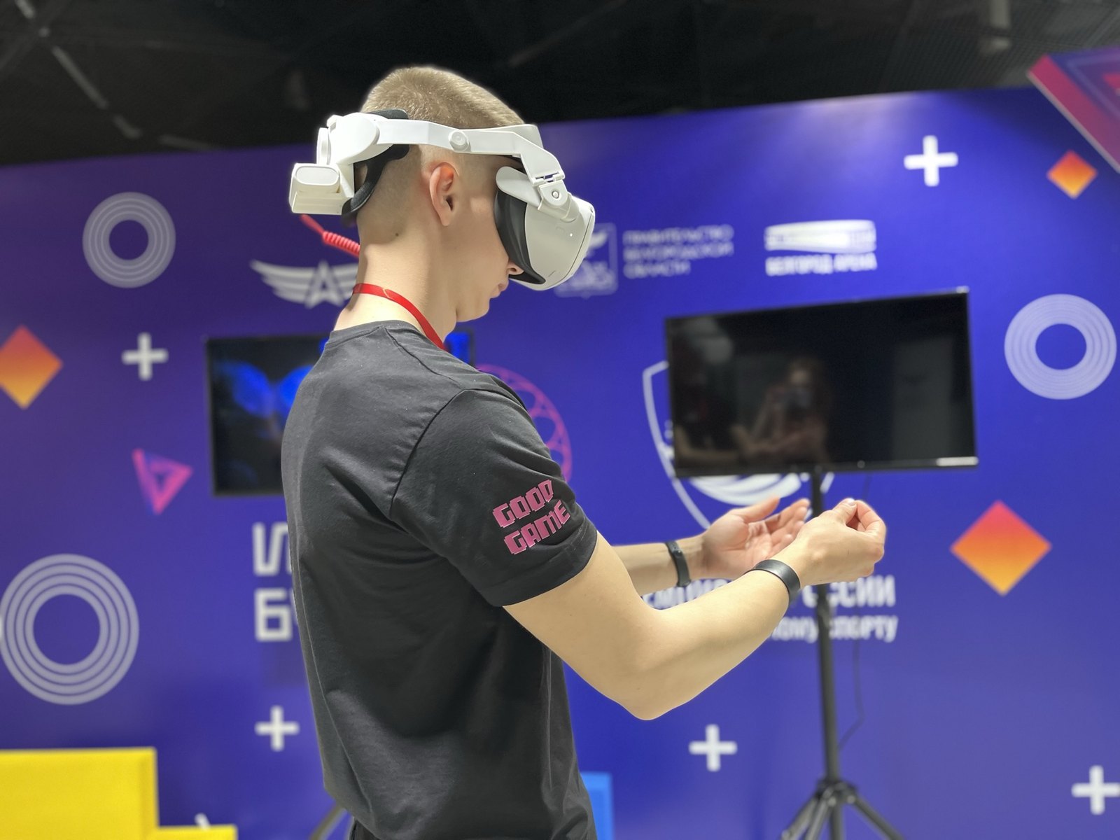 Посетитель выставки в VR-шлеме на стенде, игра дублируется на экране