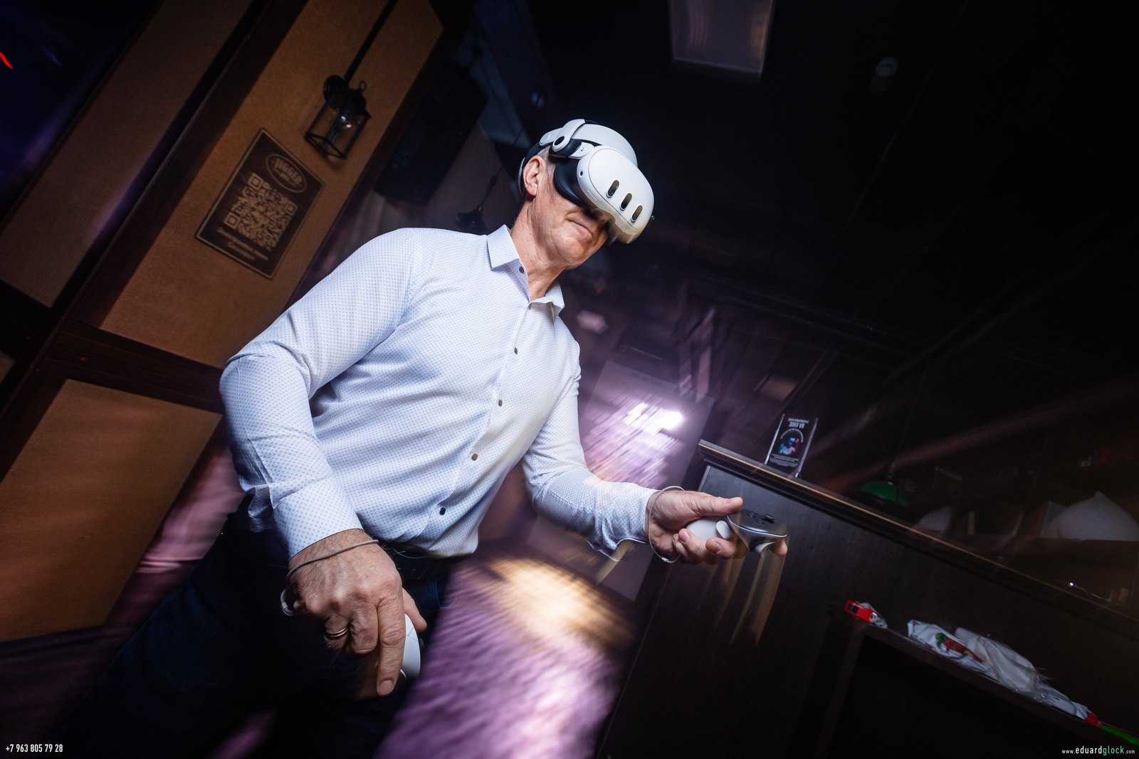 Гость в VR-шлеме играет в затемнённом баре, зона подсвечена