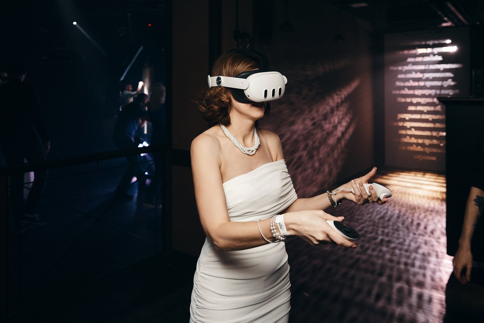 Гостья в вечернем платье играет в VR в тёмном зале