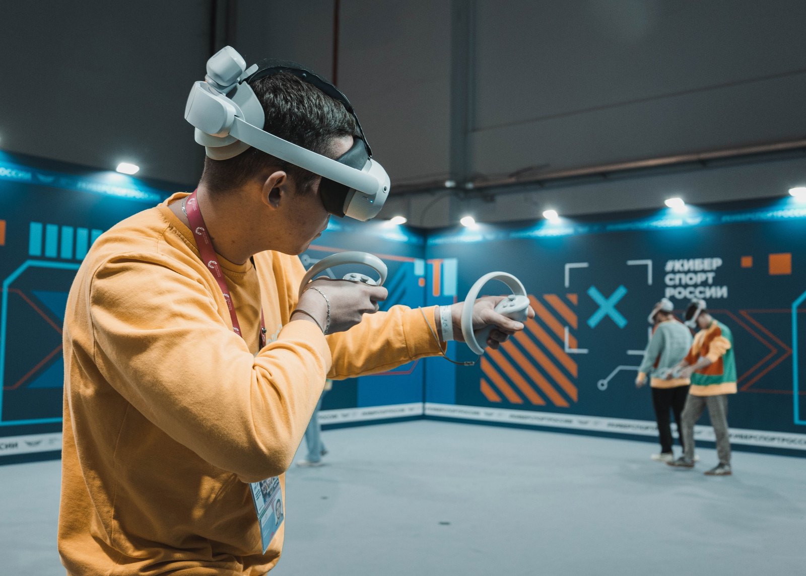 Участник турнира в VR-шлеме, на заднем плане ещё двое игроков на площадке