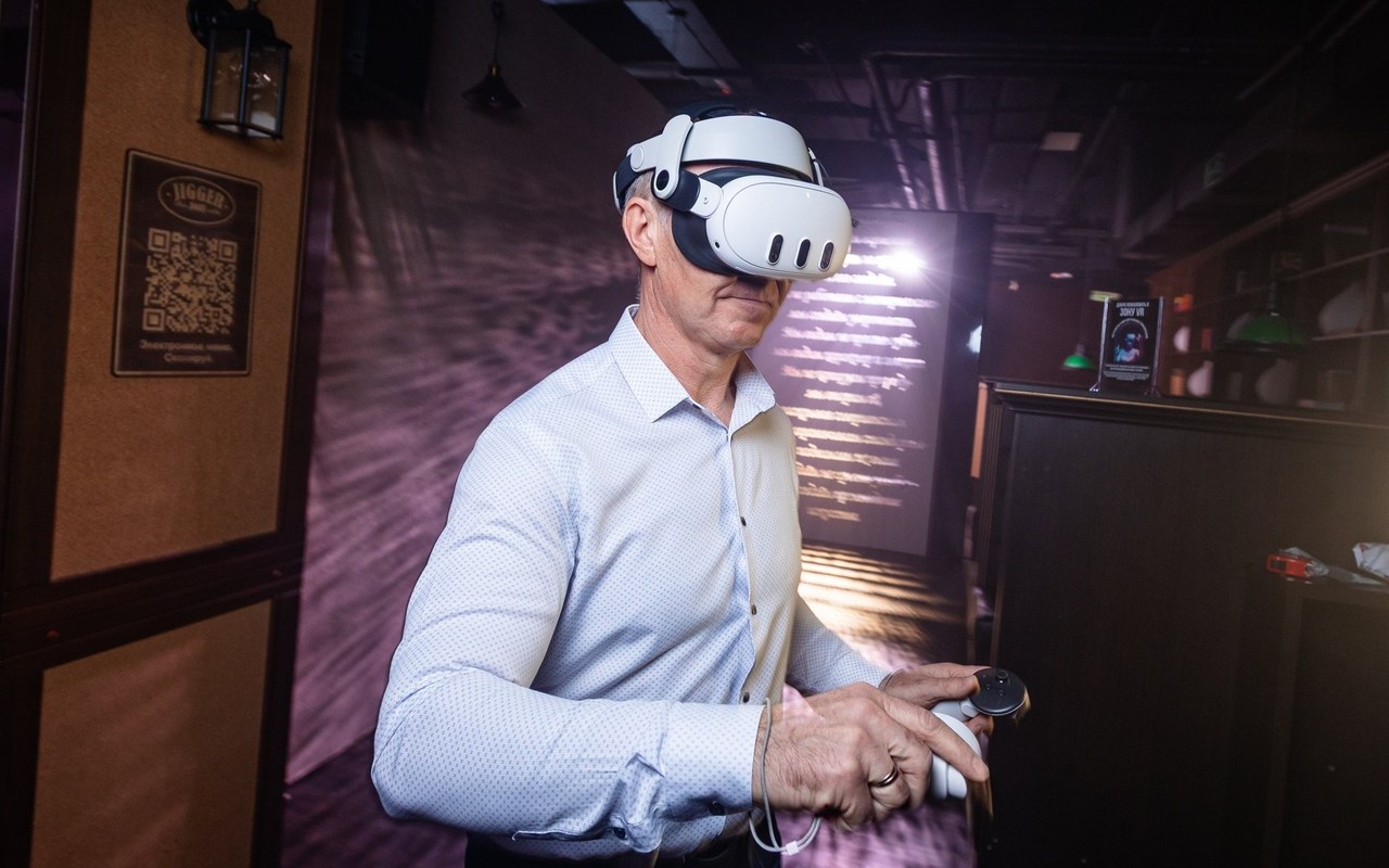 Гость в VR-шлеме играет в баре, рядом экран с трансляцией